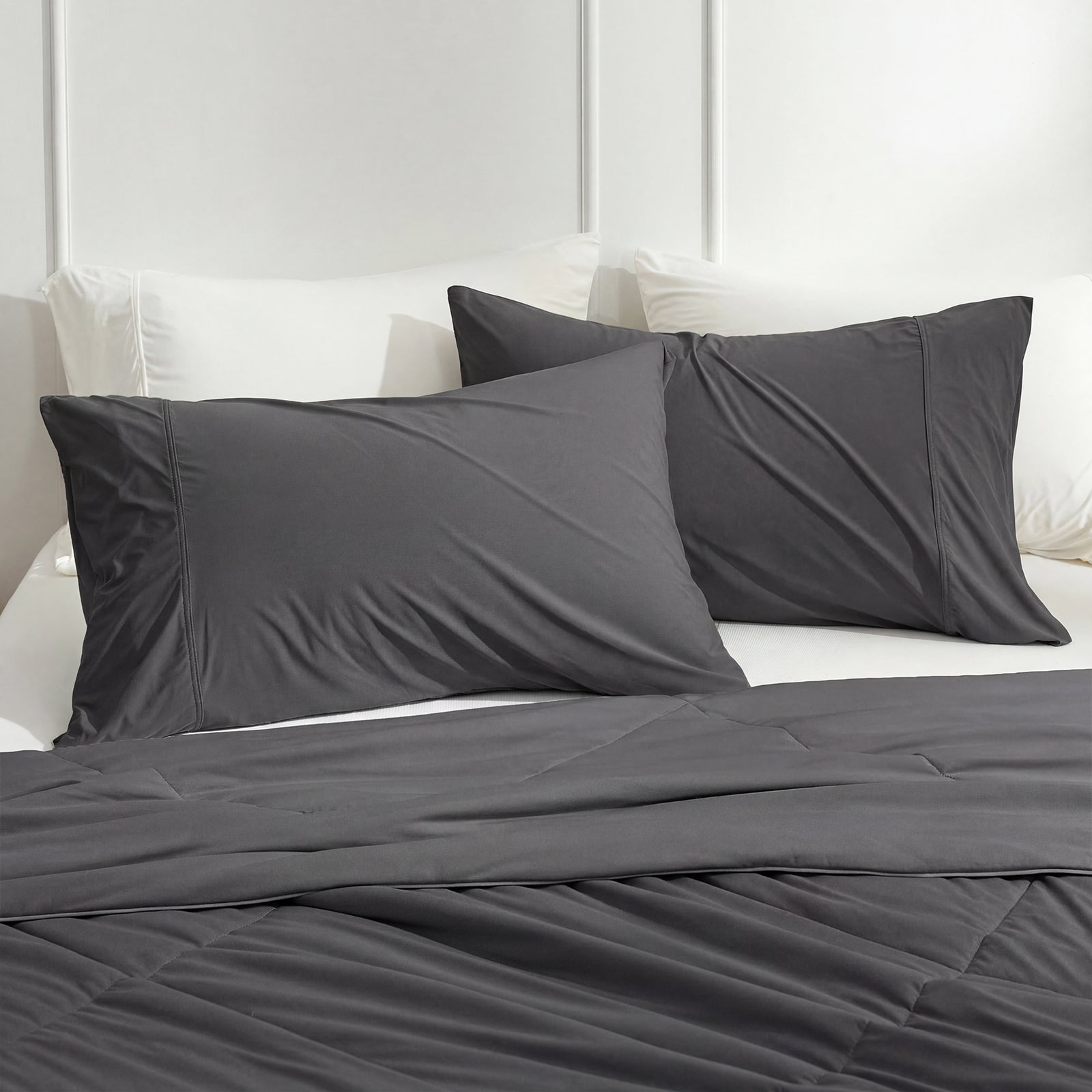 Charcoal grey cooling pillowcases on bed with cozy comforter.#color_Charcoal Grey