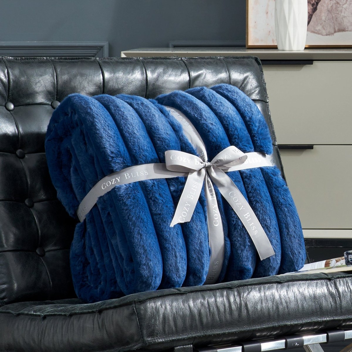 Fluffy navy blue striped faux fur blanket with a bow on a sofa.  #color_Navy Blue
