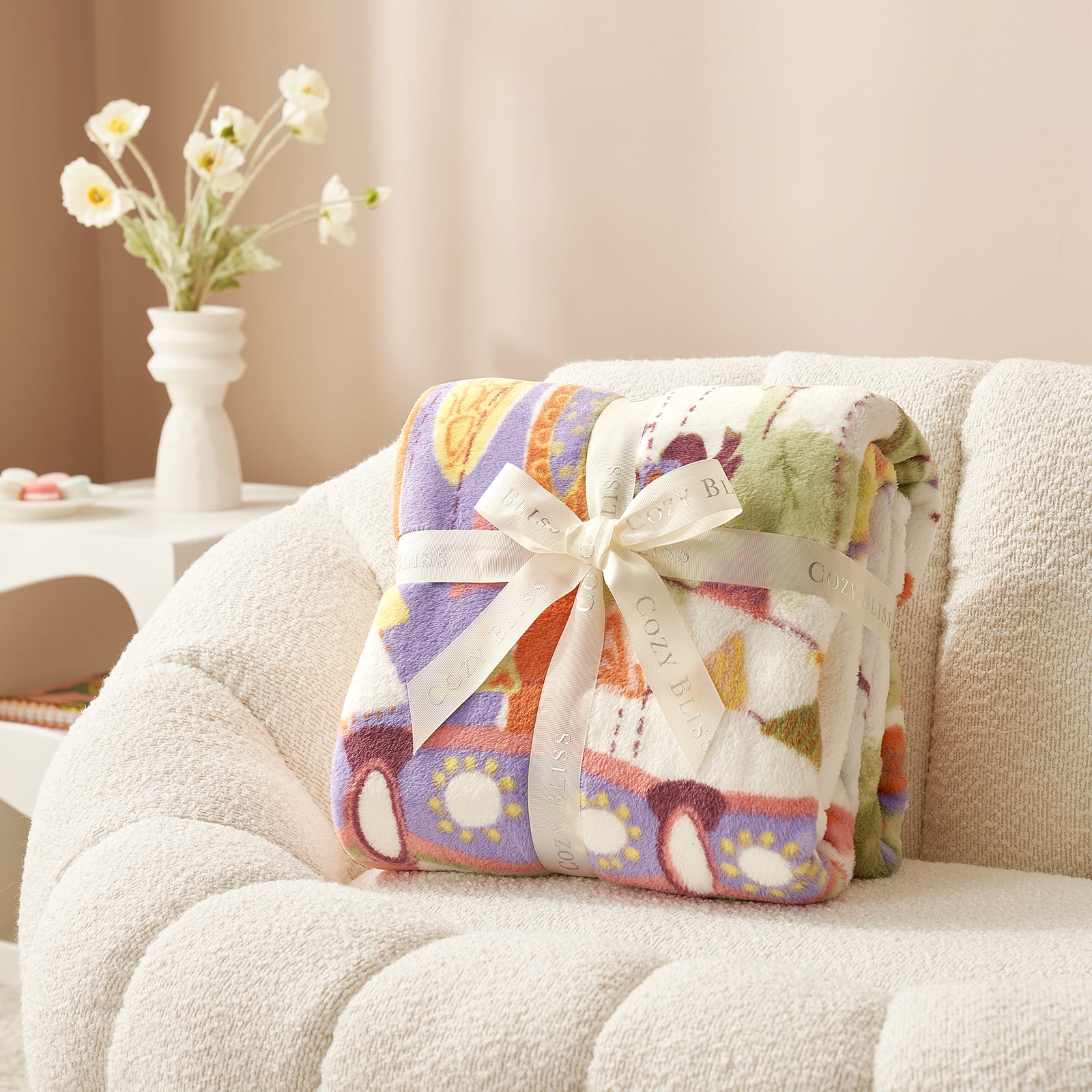 Colorful blanket with a bow on a white couch, with a vase of flowers in the background. #color_Lamb Playground