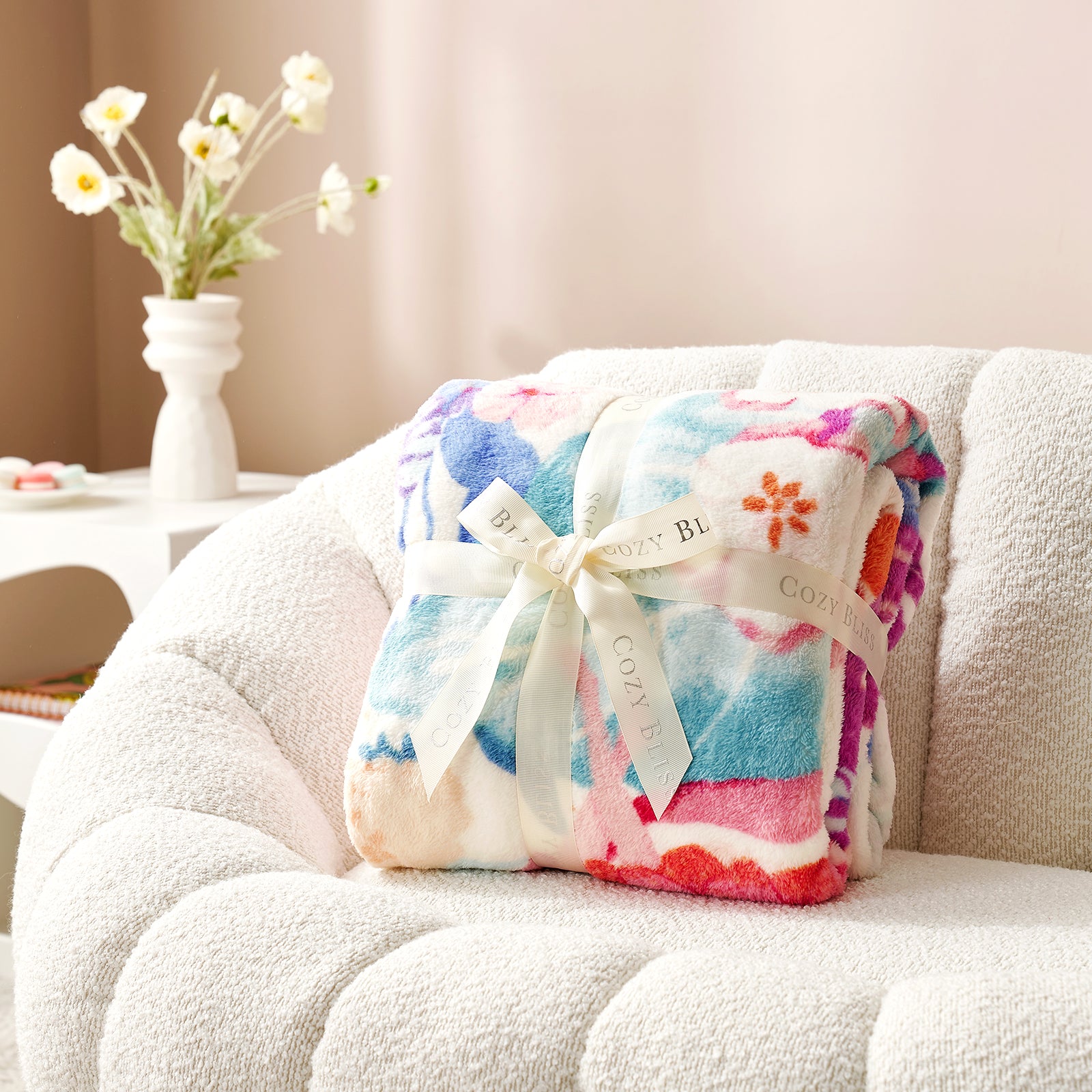 Colorful blanket with a bow on a white couch, with a vase of flowers in the background. #color_Garden Fairy