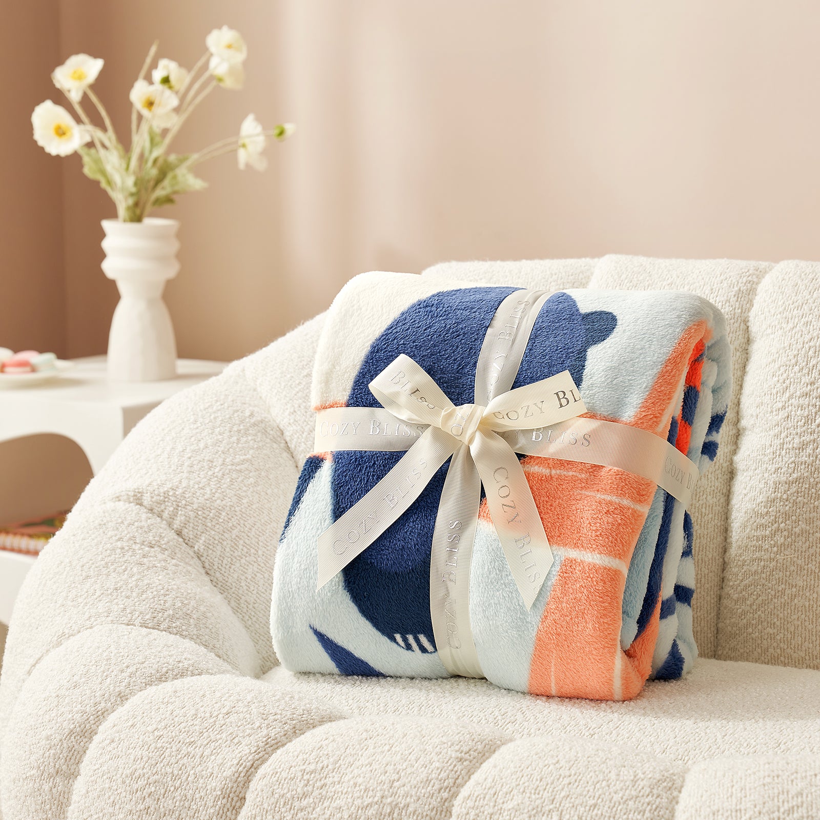 Colorful patterned blanket with a bow on a beige sofa, with a vase of flowers in the background. #color_Panda Adventure