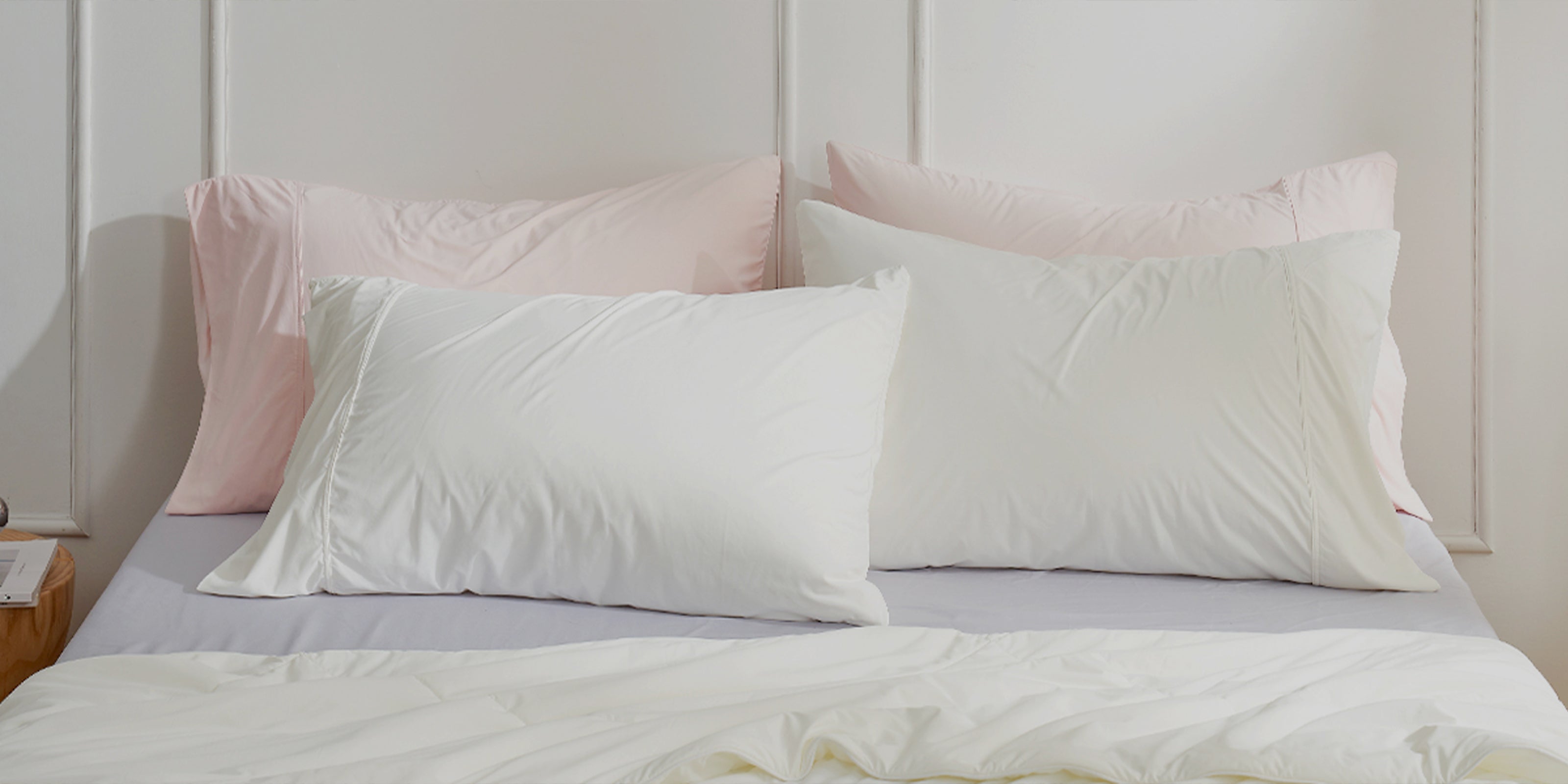 White pillows on a bed with a light pink headboard