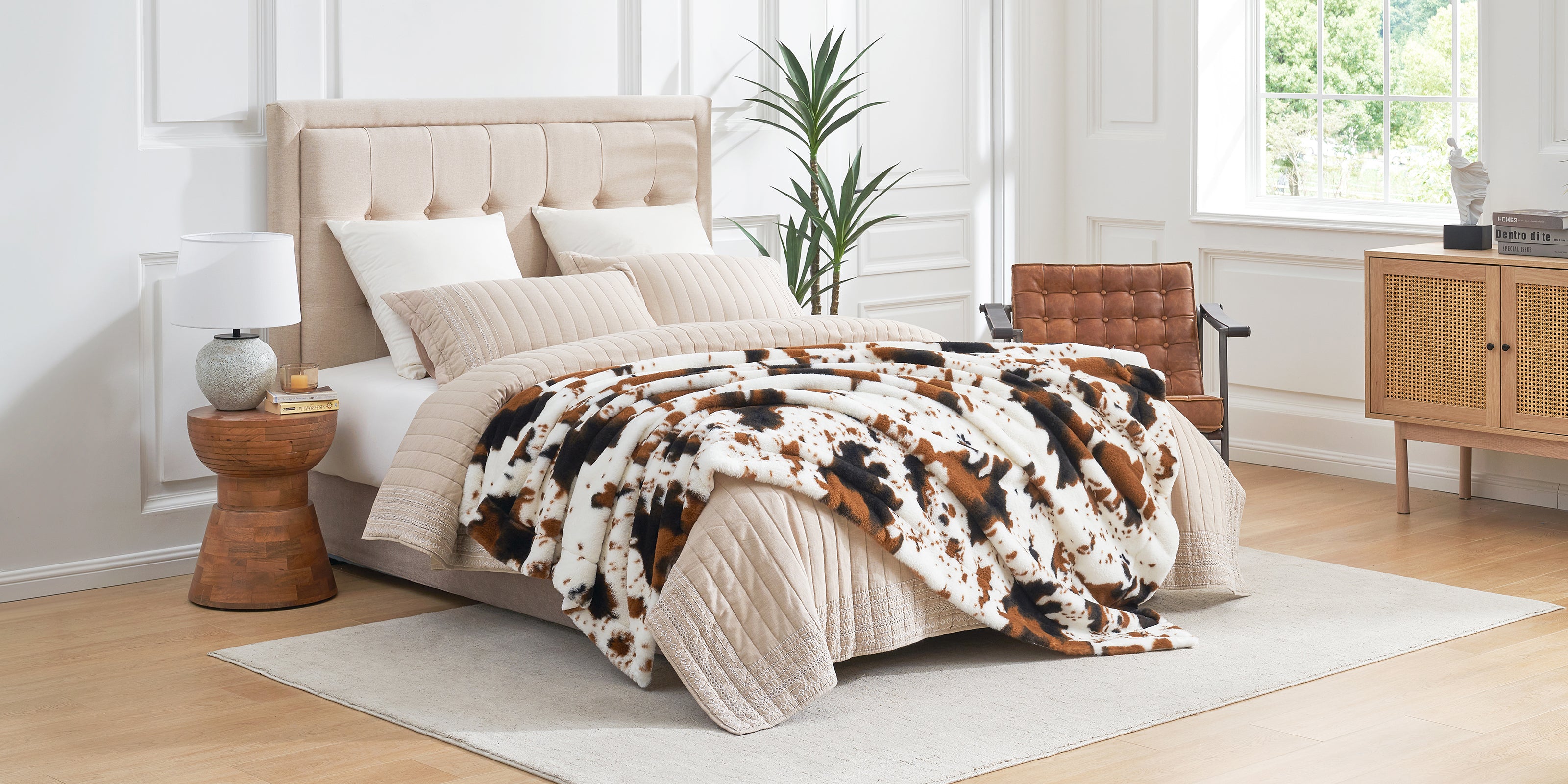 Neatly made bed with cowhide rug in a bright bedroom