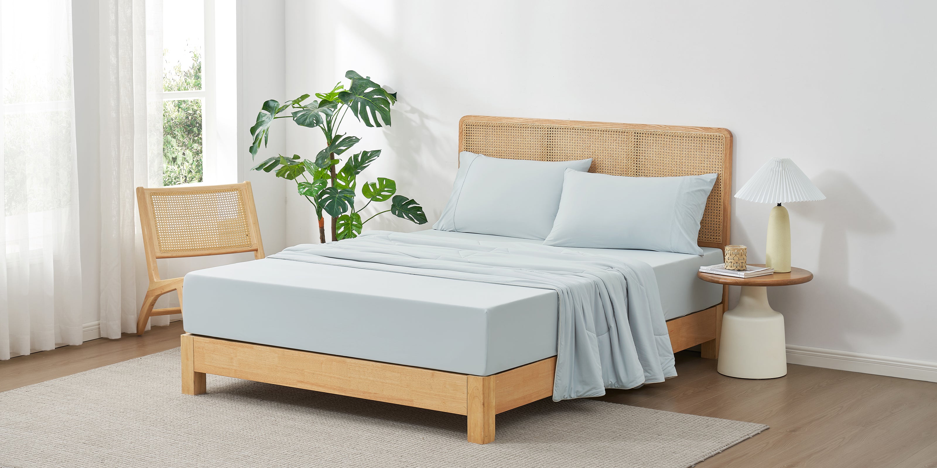 Bedroom with a wooden bed, light blue bedding, and a plant.