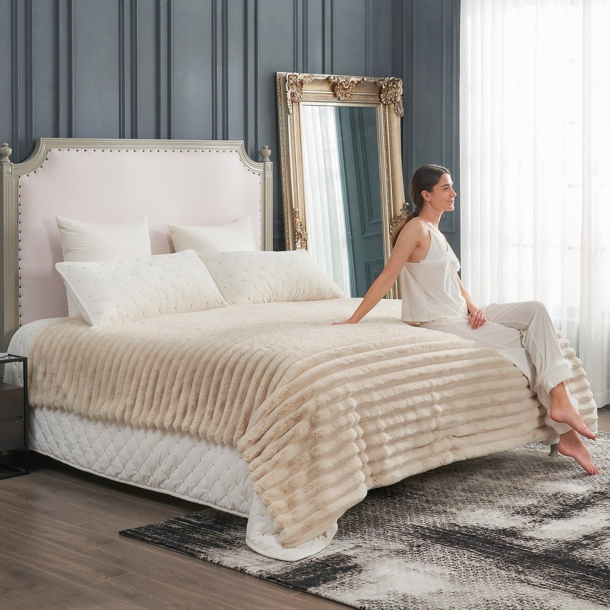 Woman sitting on a bed with Beige striped faux fur blanket, cozy bedding for luxurious comfort, soft blanket #color_Beige