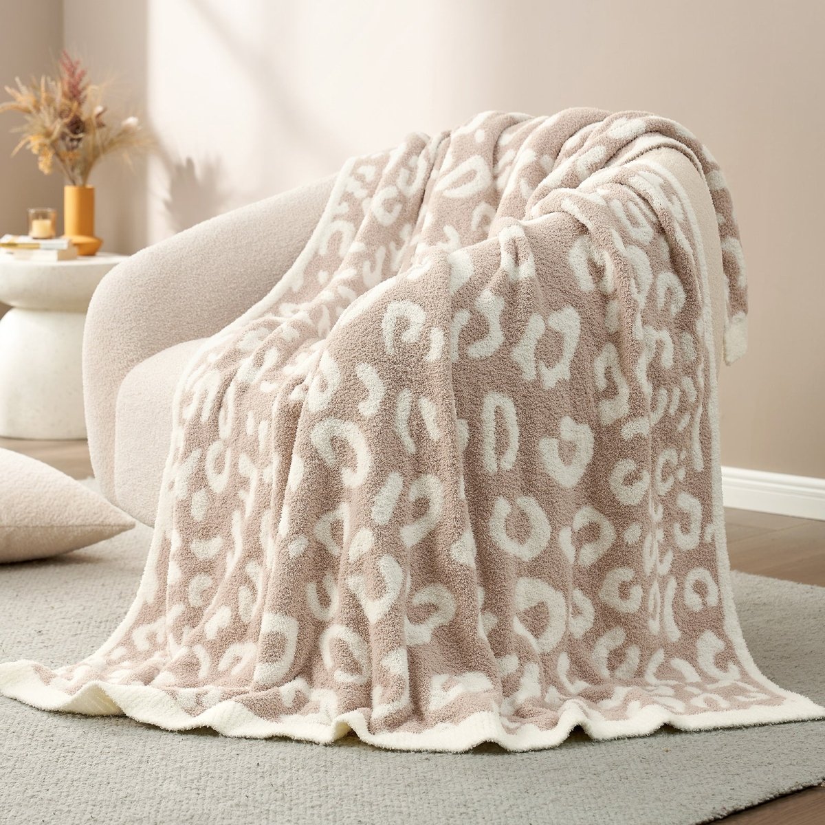 Reversible Leopard Feather Yarn Throw Blanket in Khaki Leopard draped over an armchair, showcasing its ultra soft texture and stylish leopard pattern design. #color_Khaki Leopard